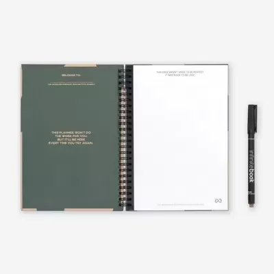 Caderno espiral aberto com capa verde escura e caneta preta ao lado