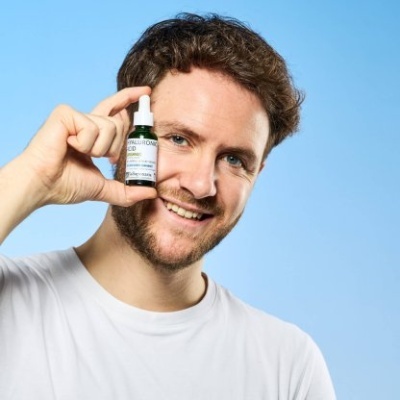 Homem com frasco pequeno de CBD com conta-gotas