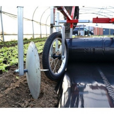 Roda de bicicleta num dispositivo agrícola numa estufa com plantas jovens e plástico preto.