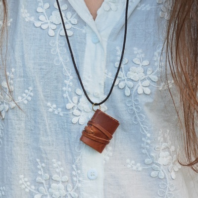 Colar com pendente de couro castanho em camisa branca bordada