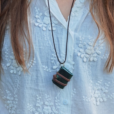 Colar com pendente retangular verde sobre camisa branca bordada