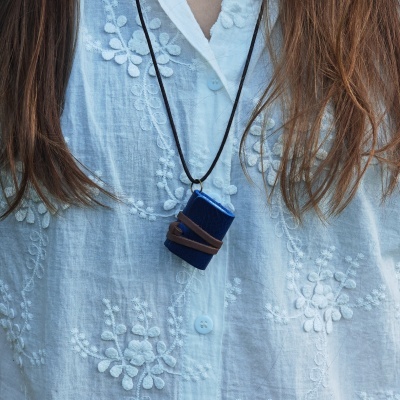 Colar com caixa azul de veludo pendurado em camisa branca bordada