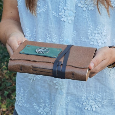 Caderno artesanal de couro castanho com placa verde e árvore metálica