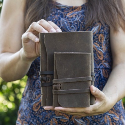 Duas carteiras de couro castanho escuras seguradas por uma mulher
