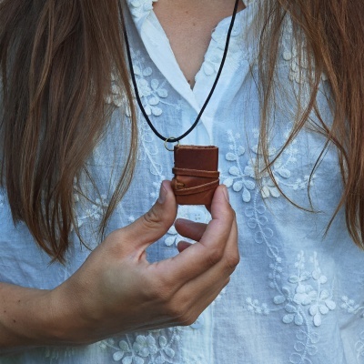 Colar com pendente mini livro em couro castanho com cordão preto, usado com camisa branca bordada
