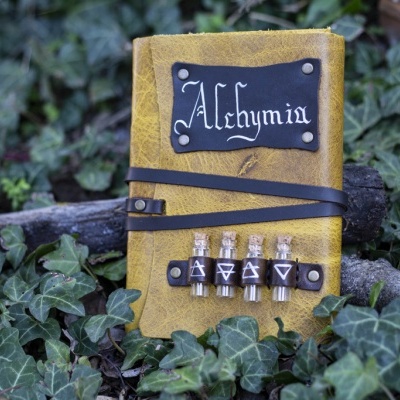 Caderno amarelo de couro com faixa preta e frascos decorativos, na hera