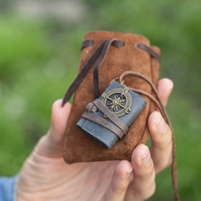 Saco castanho em camurça com cordão e marcador de livro em couro com bússola em metal