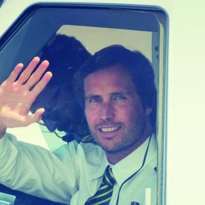 Homem a acenar da janela de um veículo com camisa e gravata