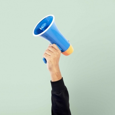 Mão segurando megafone azul com borda laranja