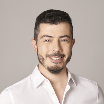 Homem com camisa branca de botões e cabelo curto, fundo cinza