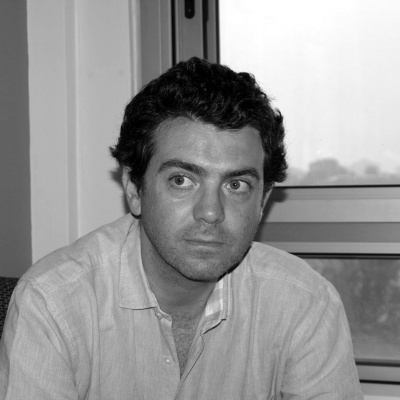 Homem com camisa clara sentado junto a janela de vidro