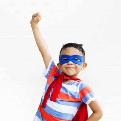 Criança em traje de super-herói com capa vermelha e máscara azul