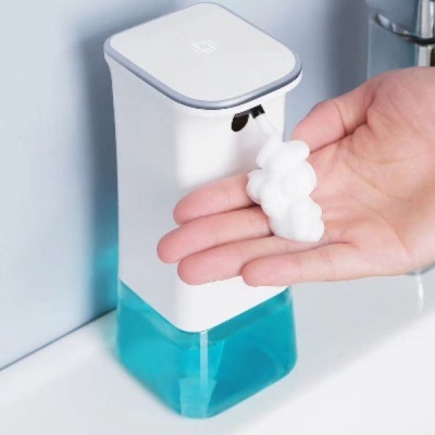 Dispenser automático branco e azul a dispensar espuma sobre uma mão
