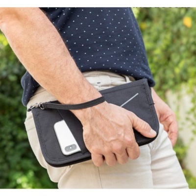 Carteira preta com telemóvel e mão segurando, em ambiente exterior