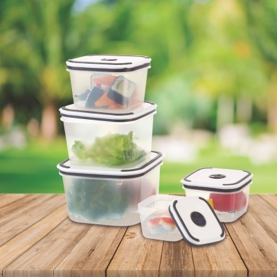 Conjunto de caixas plásticas transparentes com tampas brancas e bordas pretas contendo alimentos, sobre mesa de madeira ao ar livre