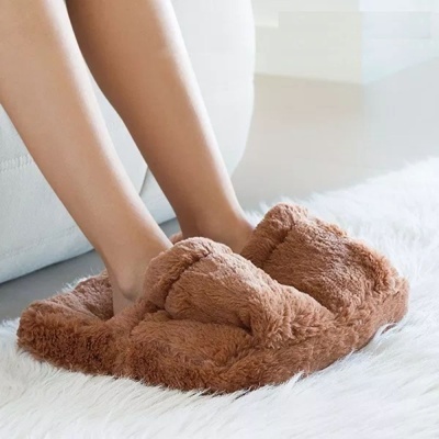 Pantufas castanhas de pelo macio usadas por uma pessoa numa sala