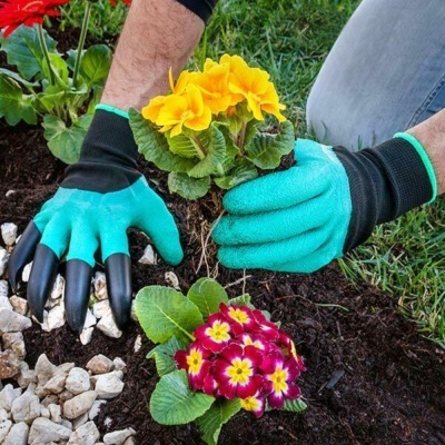 Luvas de jardinagem azuis com garras a plantar flores coloridas em terra