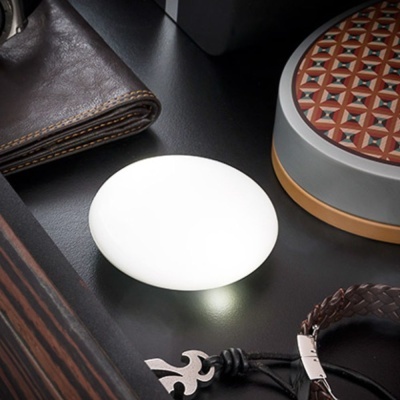 Mesa com carteira de pele castanha, caixa decorativa com padrão, pulseira trançada e objeto branco oval