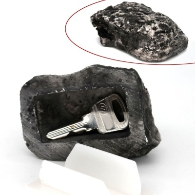 Porta-chaves em forma de pedra preta com chave metálica prateada em fundo branco