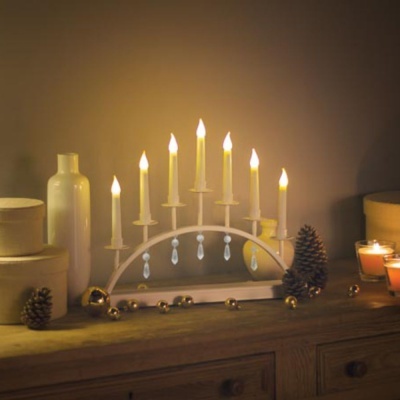 Candeeiro decorativo em arco com velas elétricas em ambiente acolhedor