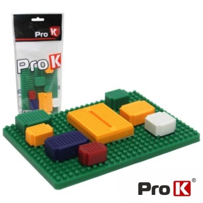 Conjunto de peças de construção coloridas sobre base verde com embalagem Pro K ao fundo