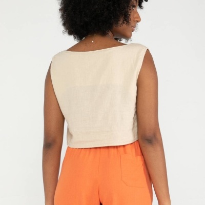 Top feminino sem mangas bege claro com calças largas laranja, visto de costas