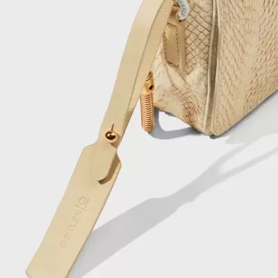 Mala bege com textura entrelaçada, fecho dourado e etiqueta DAKOTA.