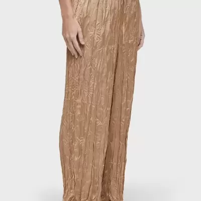 Calças compridas bege franzidas com cós elástico e cordão usadas com t-shirt branca e ténis brancos