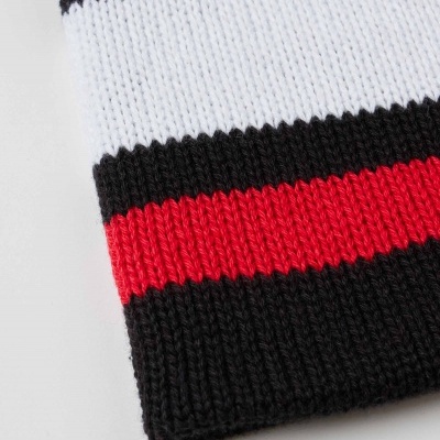 Pormenor de peça de malha com riscas em preto, branco e vermelho