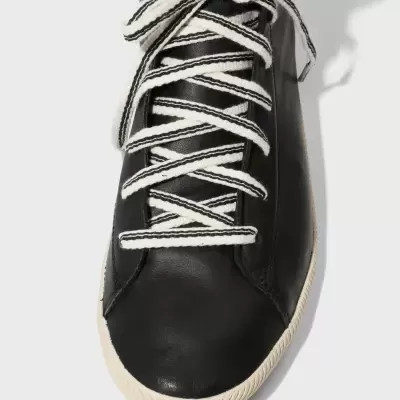 Ténis preto com atacadores brancos e sola branca