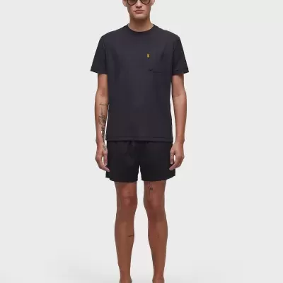 Homem com roupa preta casual e sandálias pretas em fundo branco