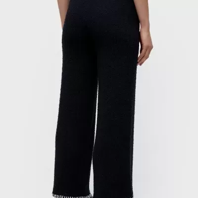 Calças pretas largas com textura e franjas brancas na bainha