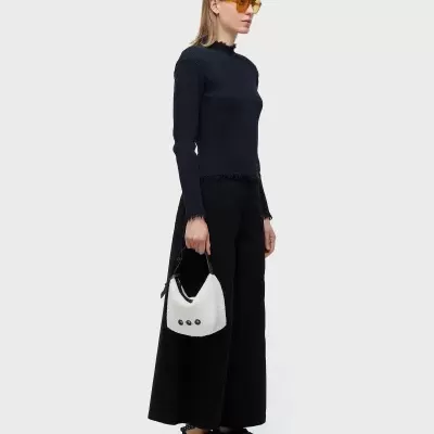 Mulher com roupa preta, óculos amarelos e mala branca