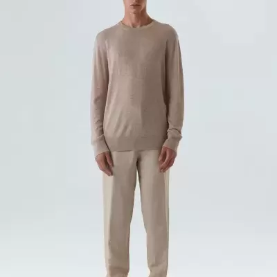 Homem com camisola e calças bege em fundo branco