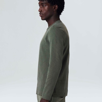 Homem de perfil com camisola verde de malha canelada e mangas compridas