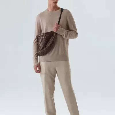 Homem com roupa bege e bolsa transversal castanha texturizada