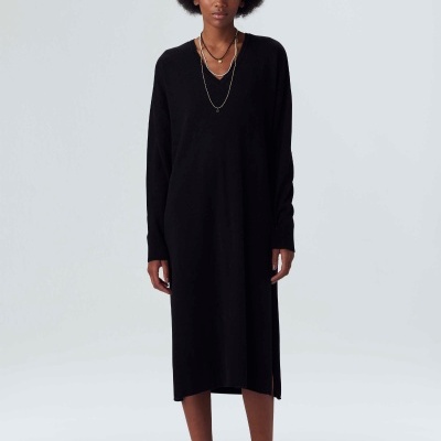 Vestido midi preto de malha com decote em V, mangas compridas e fendas laterais, usado pela modelo sobre fundo branco.