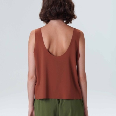 Blusa sem mangas cor tijolo vista de costas com calças verdes