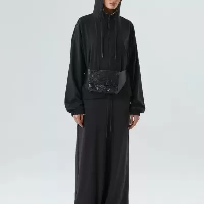 Mulher com hoodie preta, saia comprida e mala de cintura preta