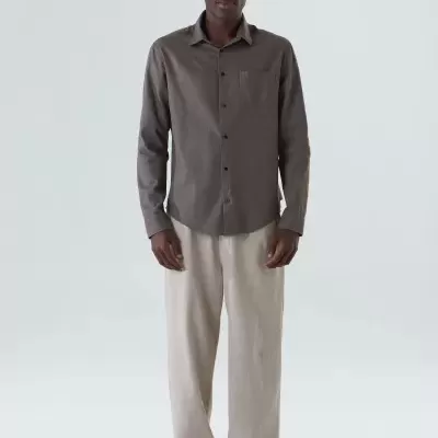 Homem com camisa castanha e calças bege