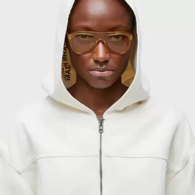 Pessoa com capuz branco de casaco com zip e óculos castanhos