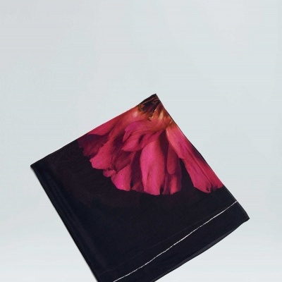 Pano dobrado com padrão de flores cor de rosa e vermelhas sobre fundo preto