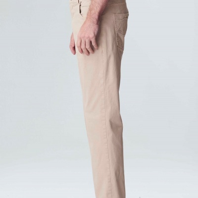 Calças bege claras com bolsos e sandálias pretas usadas por homem de perfil