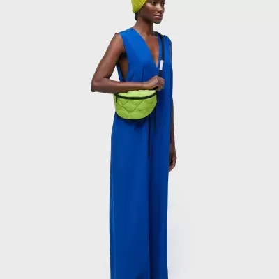 Mulher vestindo macacão azul, touca verde neon e bolsa verde neon acolchoada