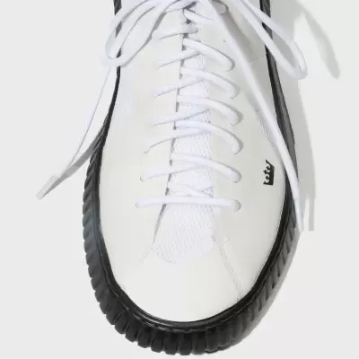 Tênis branco com sola preta e símbolo de coroa