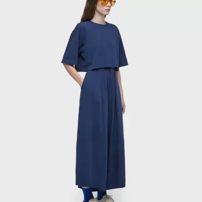 Mulher a usar conjunto azul escuro com óculos amarelos e sapatilhas claras.