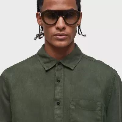 Homem com camisa verde e óculos de sol castanhos escuros