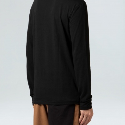 Pessoa vista de costas usando t-shirt preta de manga comprida e calças castanhas com bolso preto