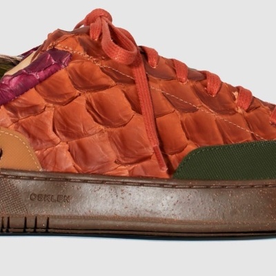 Ténis com textura de escamas laranja e detalhes em verde e castanho com a marca OSKLEN na sola