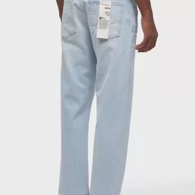 Jeans masculinos azul claro com etiqueta branca pendurada e sapatos brancos